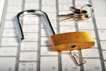 The concept of a strong password and protecting computers from hacking, the padlock is opened with a paper clip, keyboard and keys in the background