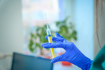 Close view of hand in blue protective glove with syringe in it on a colorful background. Good skilled doctor getting ready to give a vaccine shot. Medical concept. an experienced doctor getting ready 