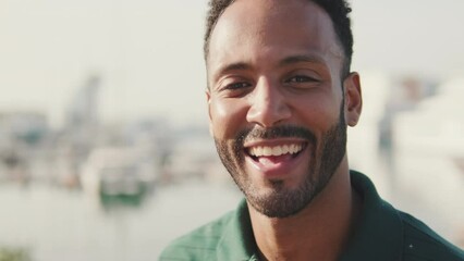 Close up, young laughing happy man in harbor with yachts on background