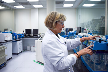 Smiling mature scientist woman wearing lab coat and glasses working in production research...