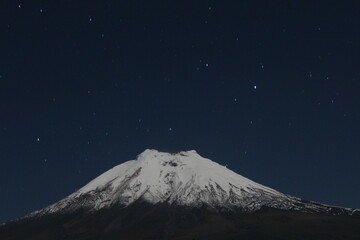 Fototapeta na wymiar Un volcan grande e imponente en la noche con un cielo estrellado. 