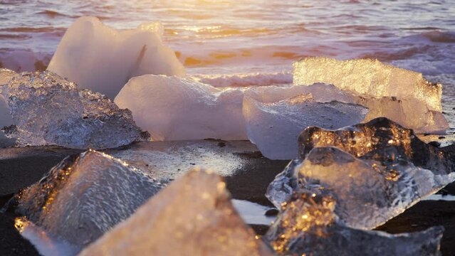 Diamond Beach in Iceland, Icebergs Shining on Black Volcanic Sand at Sunset, Clear Pieces of Glacier Ice Crashed by Ocean Waves During Sunrise. Touristic place in Europe. Shot in 8K Resolution 4320p