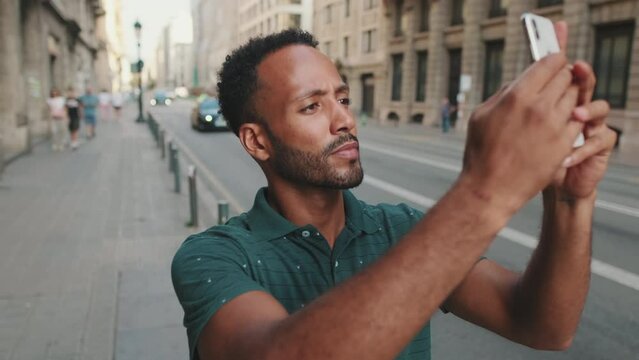 Young man takes selfie while standing on the street next to the road