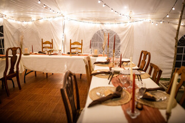 Amazing Out of the box wedding venue tent with dinner equipment on tables and warm fairy string lights