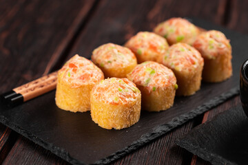 Sushi roll with mayonnaise sauce served on black board and soy sauce.