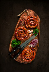 Fried spiral sausages, on a wooden board, top view, with spices, no people