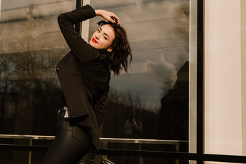 Pretty woman posing near glass building. Girl dressed casual outfits with red lips. Fashion, make up, hairstyle
