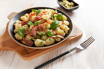 Traditional homemade cooked italian potato gnocchi baked with bacon, parsley on white background.