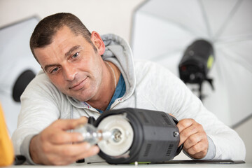 Obraz premium photographer prepares flash unit and studio light
