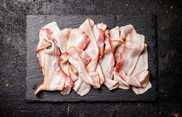 Pieces of fresh bacon on a stone board. 