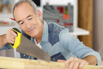 senior man sawing a log handsaw closeup
