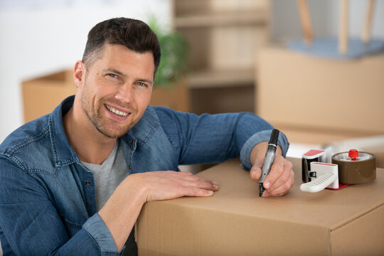 happy man is writing on a box