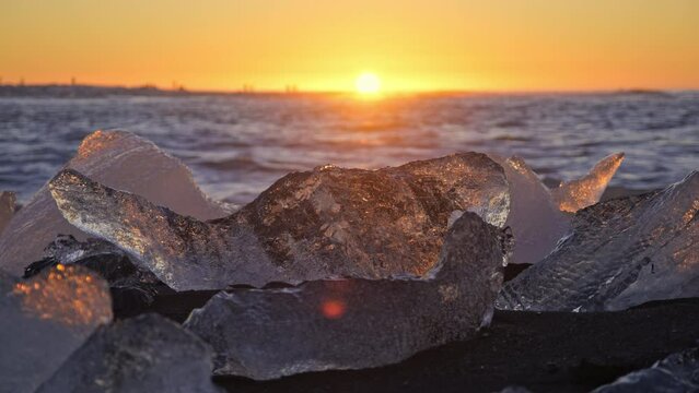 Diamond Beach in Iceland, Icebergs Shining on Black Volcanic Sand at Sunset, Clear Pieces of Glacier Ice Crashed by Ocean Waves During Sunrise. Touristic place in Europe. Shot in 8K Resolution 4320p