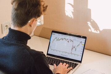 Young casual entrepreneur examines the effects of world events on the charts of the world's leading stock market indices. The life of a stock trader