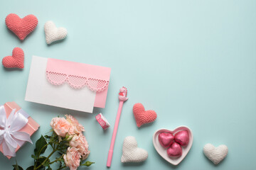 A banner with a gift, a bouquet of roses, an envelope, tape, a pen and knitted hearts on a light blue background.