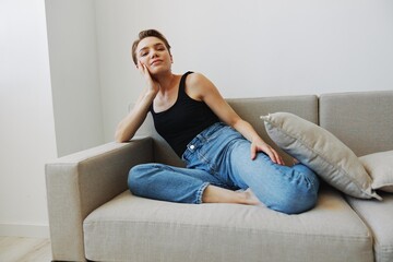 Fototapeta premium Young woman with short haircut hair having fun at home on the couch smile and happiness, vacation at home, natural posing without filters, free copy space