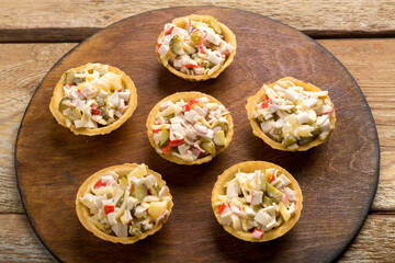 salad with shrimps in tartlets on a board on a wooden table.