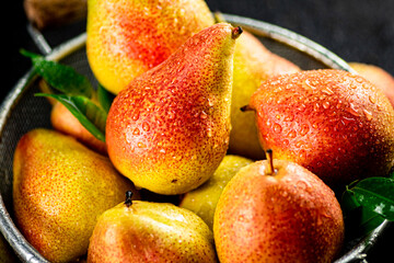 Fresh pears with leaves in a colander. 