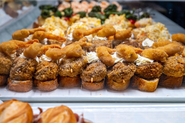 Typical snack of Basque Country, pinchos or pinxtos, small piece of bread with different fish and sea food toppings, served in bar in San-Sebastian or Bilbao, Spain
