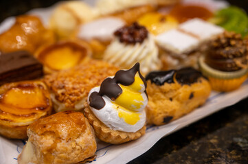 Delicious fresh baked colorful decorated cakes, tarts with cream and fruits on display in bakery in Bilbao, Basque Country, Spain