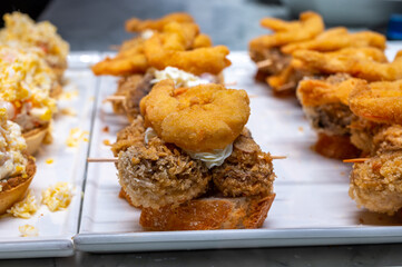 Typical snack of Basque Country, pinchos or pinxtos, small piece of bread with different fish and sea food toppings, served in bar in San-Sebastian or Bilbao, Spain