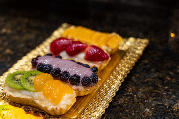 Delicious fresh baked colorful decorated cakes, tarts with cream and fruits on display in bakery in Bilbao, Basque Country, Spain