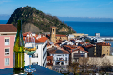 Tasting of txakoli or chacolí slightly sparkling very dry white wine produced in Spanish Basque Country with view on old port and village Getaria, Spain