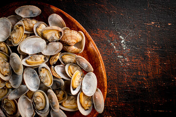 A wooden plate full of fresh vongole. 