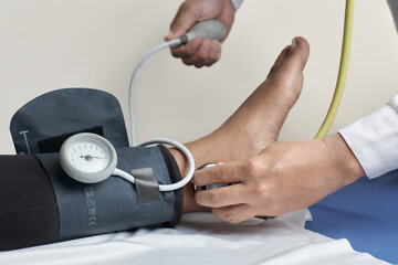 physician taking blood pressure in lower limb and foot of unrecognizable patient