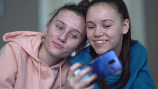 Two female sisters taking selfie photos for social media on smartphone
