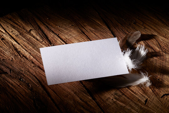 Mockup business card on rustic wood and fethers
