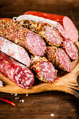 Different types of salami sausage on a wooden cutting board. 