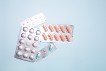 Tablets in blister and pills jar package on blue background.
