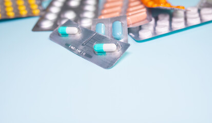 Tablets in blister and pills jar package on blue background.