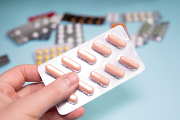 Male Hand Holding Tablet Of Pills,  On Blue Background.
