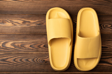 Rubber summer slippers. Replacement shoes for home or office. Yellow slippers on a background of brown space. Relax concepts. Space for text.Space for copy.