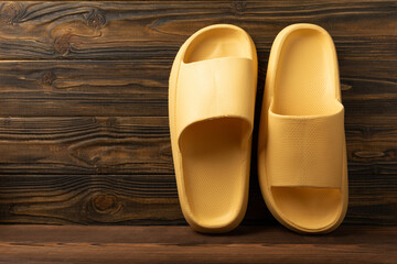 Rubber summer slippers. Replacement shoes for home or office. Yellow slippers on a background of brown space. Relax concepts. Space for text.Space for copy.