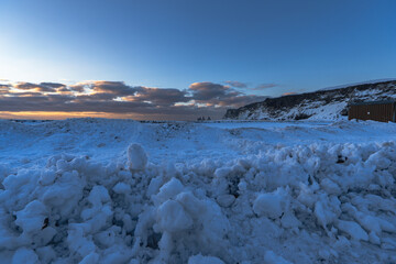 Landscape of the beach area Totally snow covered black sand beach with golden sunrise light under the clouds