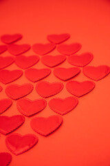 Red satin hearts on a red background. St. Valentine's Day background. Top view, selective focus