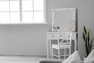 Table with cosmetics and mirror in light makeup room