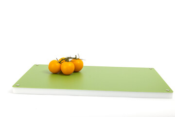 Vegetables on green professional chopper  - yellow cherry tomatoes