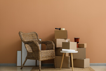 Moving cardboard boxes with table and armchair near color wall