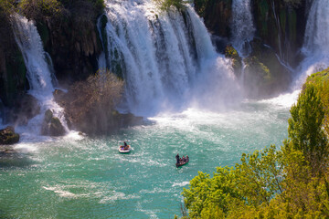 Small boat rowing just under Kravica waterfalls in southern Bosnia and Herzegovina
