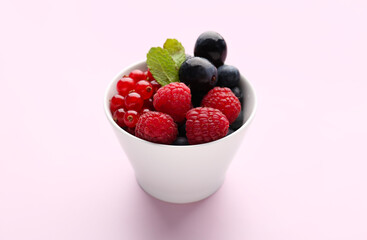 Bowl of fresh ripe berries on pink background