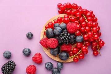 Wooden board with fresh ripe berries on color background
