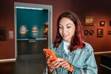Girl uses the application on her smartphone as an audio guide and a virtual tour of the Museum of...