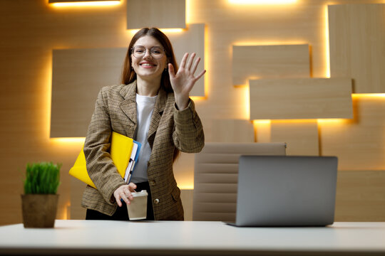 First day at the office. A young girl smiles and shows a gesture of welcome at the workplace.