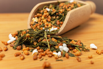 Green tea Japanese Genmaicha. Green tea mixed with roasted popped brown rice in wooden scoop on...