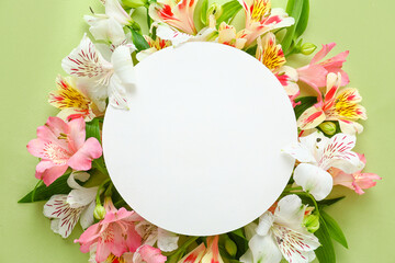Composition with blank card and beautiful alstroemeria flowers on green background, closeup....