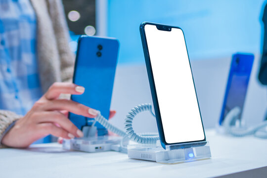Mockup image: new model of smartphone with blank white display at electronic shop, store, trade show, exhibition. Mock up, copyspace, white screen, template, technology concept